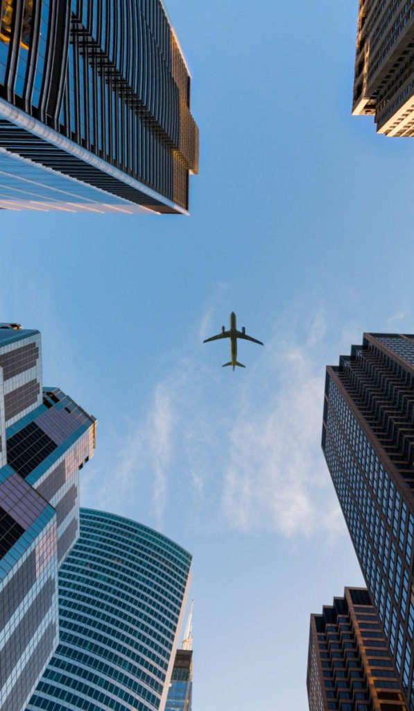 Airplane flies over Chicago's modern skyscrapers against a clear sky, highlighting urban architecture.