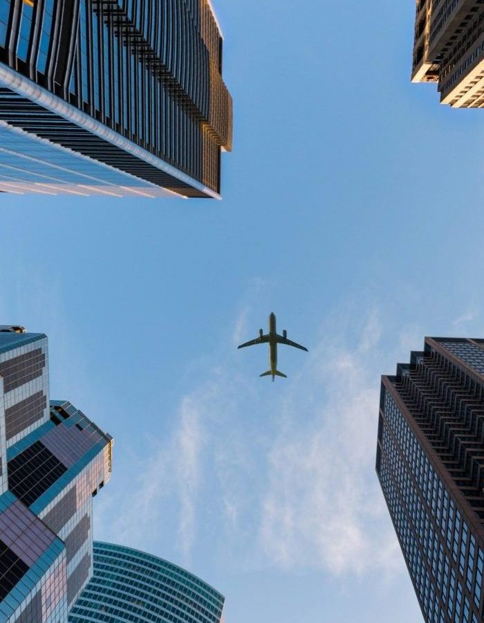 Airplane flies over Chicago's modern skyscrapers against a clear sky, highlighting urban architecture.