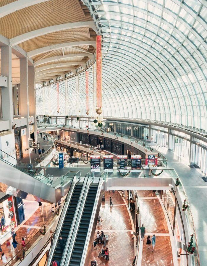Spacious indoor shopping mall with glass ceilings and a modern design, including escalators and shops.