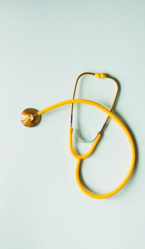 Top view of yellow medical stethoscope placed on white surface during coronavirus pandemic