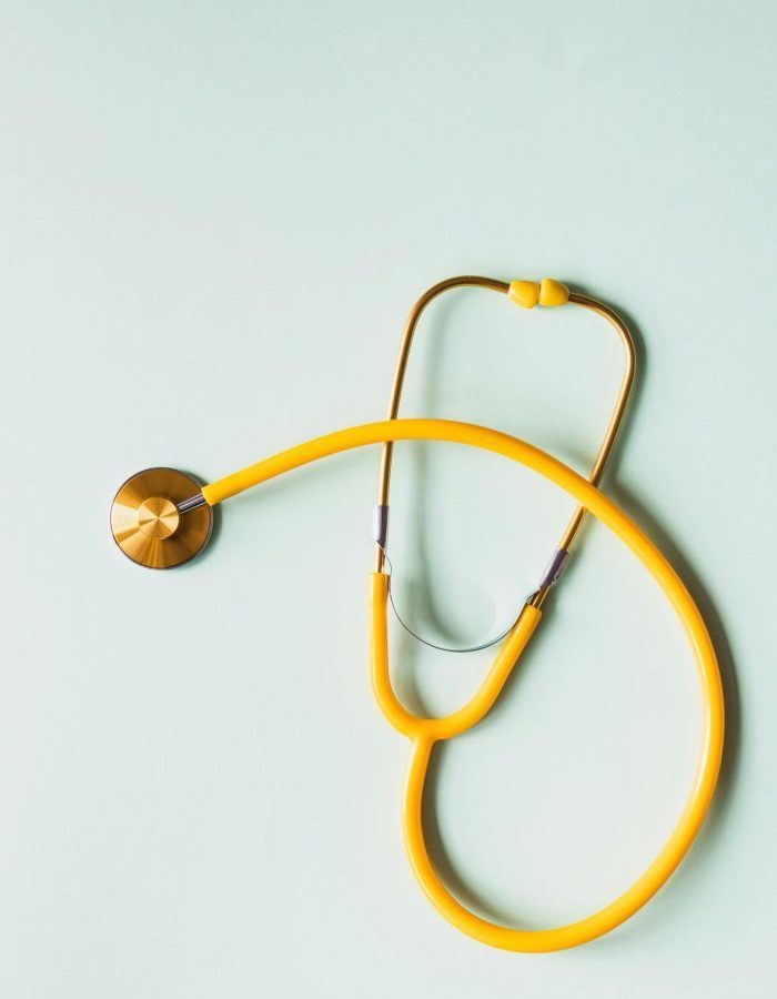 Top view of yellow medical stethoscope placed on white surface during coronavirus pandemic