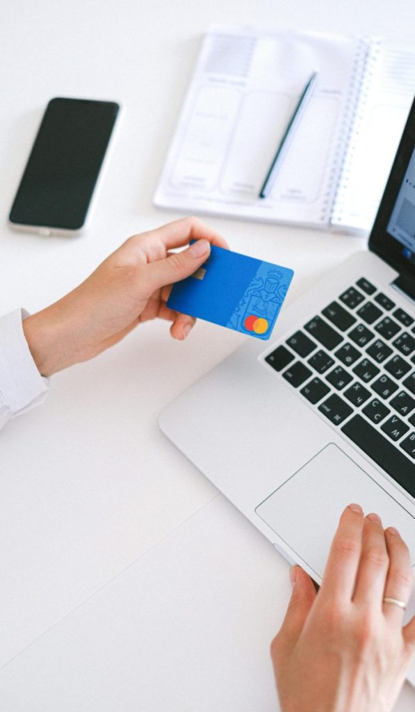 Person making an online purchase with a credit card on a laptop, showcasing modern ecommerce technology.